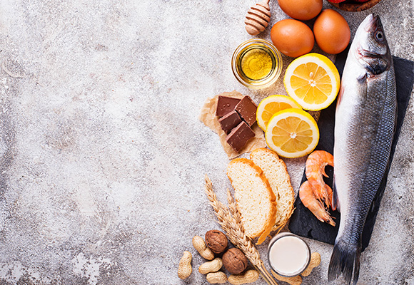 fresh fish and seafood with eggs citrus fruits olive oil bread chocolate and nuts arranged on a textured surface 8 healthy ingredients for a balanced diet